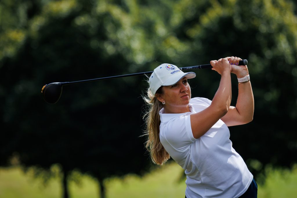 Seorang anggota tim Galloway Ladies yang mengenakan topi putih dan kaus oblong mengawasi perjalanannya setelah dia melakukan tee off di Women's County Finals di Kirkcaldy Golf Club. 
